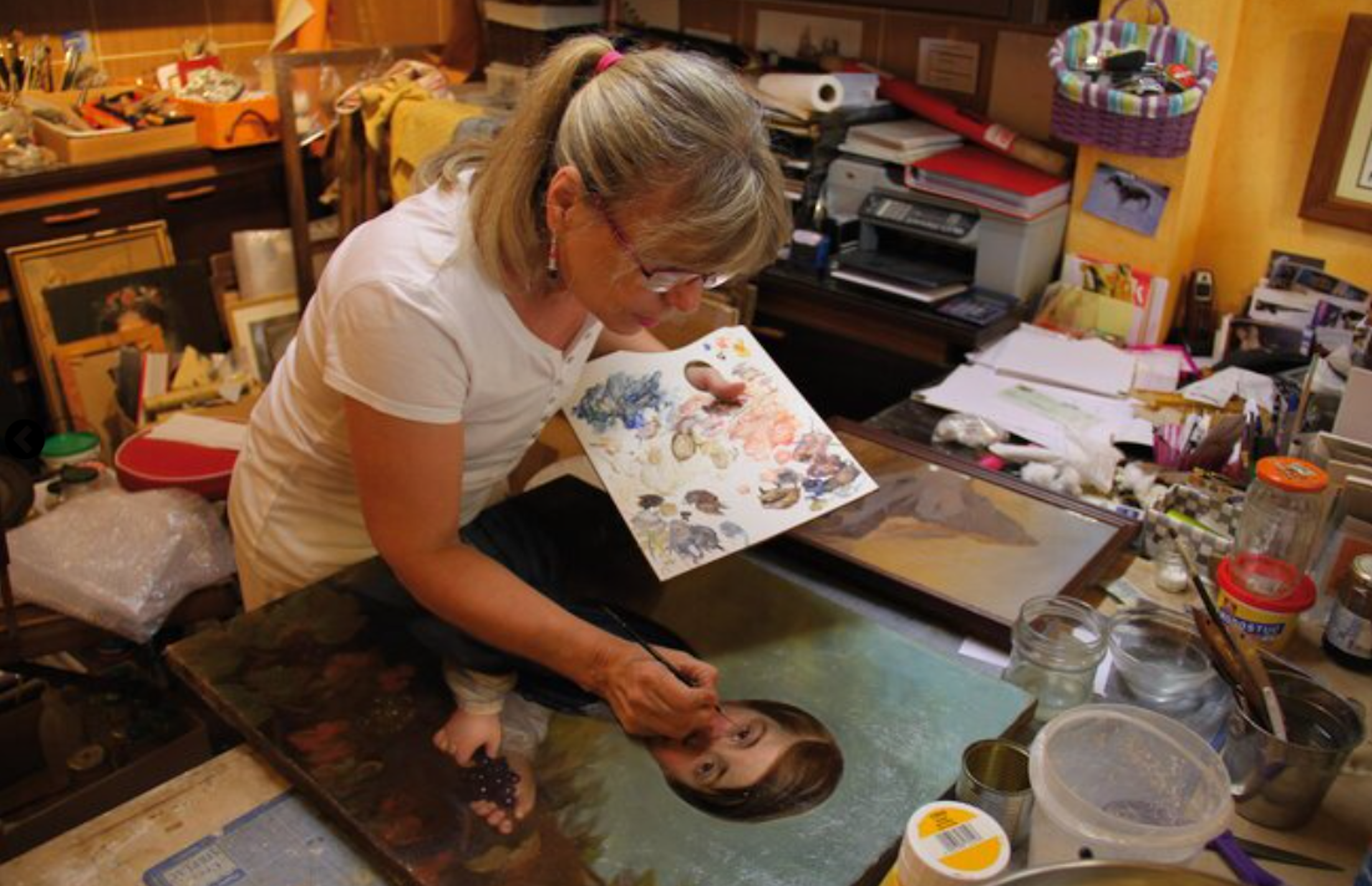 Véronique Lantrès réalise des retouches de peinture dans son atelier sur un portrait de jeune homme
